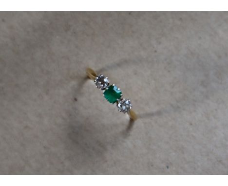 An emerald and diamond ring set with a central square cut emerald 4mm x 4mm, flanked by two round old cut diamonds to a white