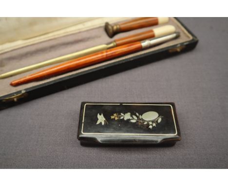 A Victorian papier mache snuff box inlaid with metal depicting a butterfly, flowers and leaves together with a part desk set 