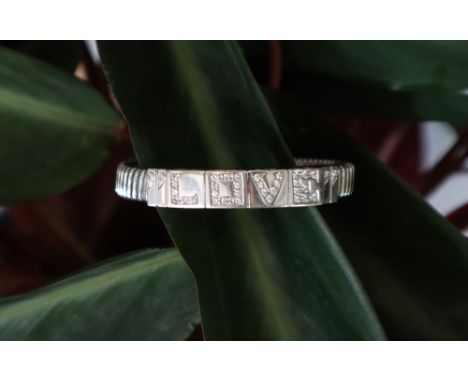 An 18ct white gold panel of a white metal elasticated bangle set with round brilliant cut diamonds spelling out "Love", appro