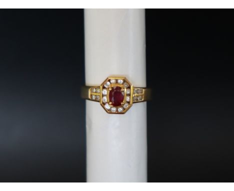 An 18ct yellow gold ruby and diamond ring, with an oval faceted ruby surrounded by round brilliant cut diamonds and diamond s