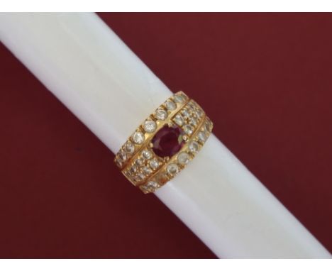 An 18ct yellow gold ruby and diamond ring, set with a central oval faceted ruby and four lines of round brilliant cut diamond