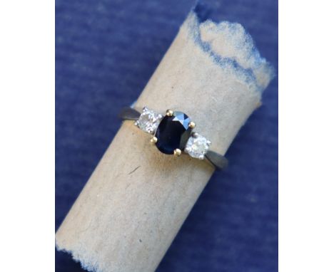 A sapphire and diamond ring set with a faceted oval sapphire, 7 x 5mm, flanked by a pair of round old cut diamonds to an 18ct