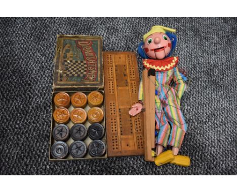 A Pelham Puppet Clown having moveable wooden mouth, a wooden Cribbage board and a set of wooden Draughts in box