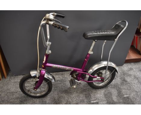 A 1970's Raleigh Budgie Child's Bike in purple with black seat, chrome mud guards, metal spoked wheels, front brake and bell,