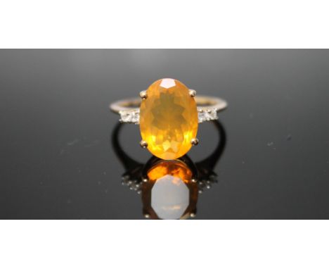 A HALLMARKED 9 CARAT YELLOW GOLD FIRE OPAL RING, with a large oval claw set fire opal measuring approx 15 mm by 10 mm and fou