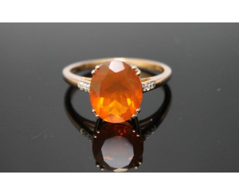 A HALLMARKED 9 CARAT YELLOW GOLD FIRE OPAL RING, with a large oval claw set fire opal measuring approx 12 mm by 10 mm and six