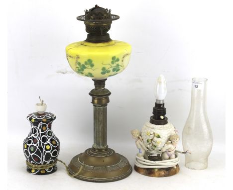 Two ceramic table lamps and an oil lamp. The oil lamp with a brass columnal base and a yellow glass reservoir painted with sh