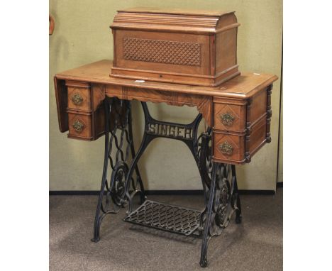 A vintage Singer sewing machine. The machine attached to a wooden top with a foldable end and multiple drawers, supported by 