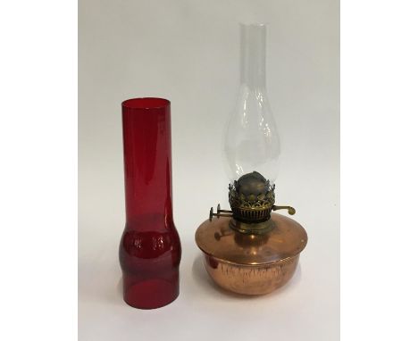 A brass oil lamp with glass chimney and non associated red glass chimney 
