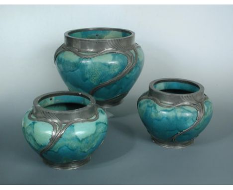 A pair of Orivit pewter mounted high-fired jardinieres, the green high fired ceramic bodies mounted with pierced scrolling pe
