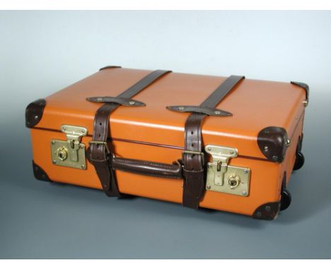 A Globe-trotter 20" pull-along suitcase, finished in orange with chestnut corners, straps and handles 55 x 40 x 20cm (21 x 16