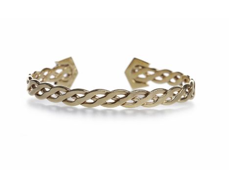 CELTIC MOTIF TORQUE BANGLE
formed by a pierced woven band with white gem set terminals, in nine carat gold, 16.8g