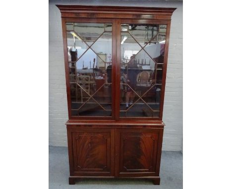 A George III mahogany bookcase cabinet, the pair of astragal glazed doors over a panel lower, on bracket feet, 126cm wide x 2