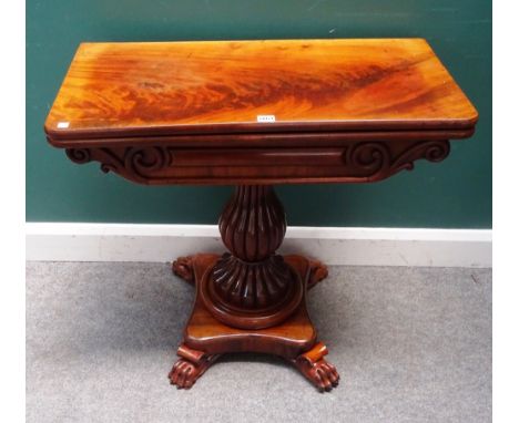 A Regency mahogany card table, the rounded rectangular top on a reeded baluster column and four paw feet, 81cm wide x 76cm hi