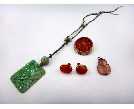 A Chinese carved jade panel shaped pendant necklace, decorated with flowers and fruit, the cord suspension decorated with see