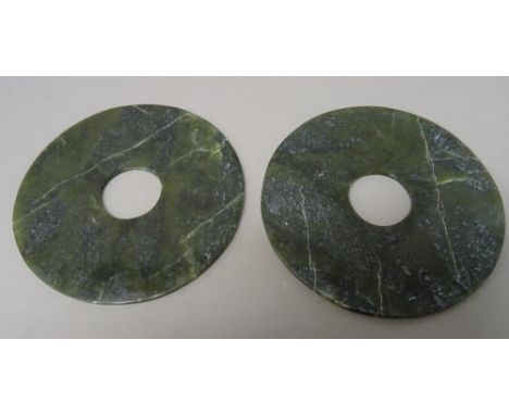 A pair of Chinese spinach jade bi discs, the stone with cream inclusions, 12cm. diameter, (2).