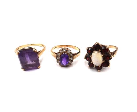 A 9ct gold ring, claw set with a cut cornered rectangular step cut amethyst, a gold, amethyst and colourless gem set oval clu