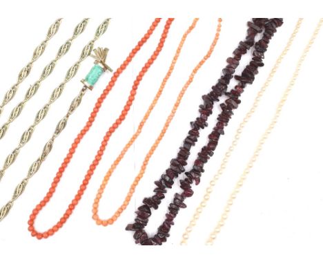 Two single row necklaces of coral beads, a single row necklace of tumbled garnet beads, a gilt metal necklace, with two pale 