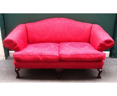 Wesley Barrell; a George I style hump back sofa, with floral patterned red upholstery and roll-over arms, on claw and ball fe