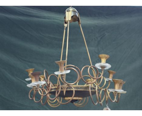 An Empire style gilt and patinated brass twelve branch chandelier, the dished body centred with a lions head roundel, suspend