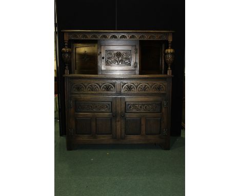 17th Century style oak court cupboard, with a lunette carved frieze above a floral panelled cupboard door flanked by bulbous 