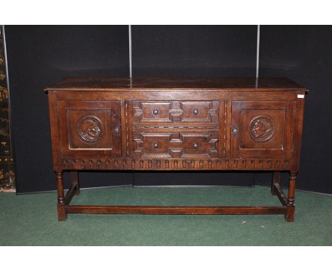 Jacobean style oak dresser base, with two central geometric moulded doors flanked by two cupboards with circular portrait pan