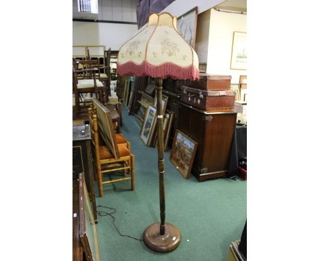 Mahogany standard lamp with tasselled shade and turned stem on a circular plinth base