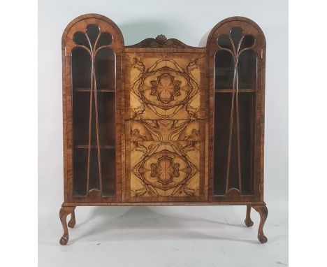 Early 20th century walnut cabinet, the double domed top with central shelf above fall, drawer and cupboard door, flanked by g