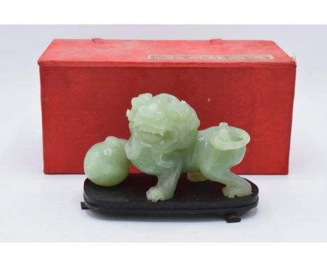 A boxed Chinese Jade (or similar) carved figure of a Dog of Fo on wooden plinth. 13cm long. In good condition with no obvious