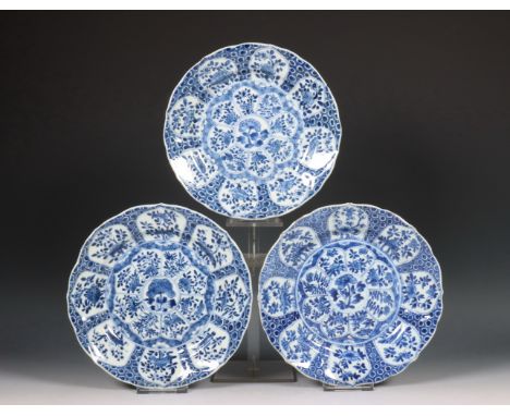 China, set van drie blauw-wit porseleinen borden, Kangxi periode (1662-1722), gedecoreerd met bloemvormige panelen gevuld met