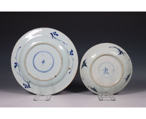 China, twee blauw-wit porseleinen borden, Kangxi periode (1662-1722), het grotere bord gedecoreerd met chrysanten en pioenen,