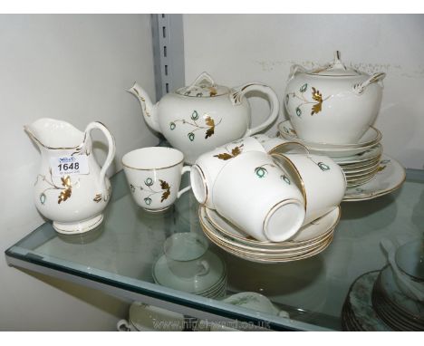 A part Victorian tea service in white with green and gold decoration, including bread/butter plate, teapot, sugar bowl, milk 