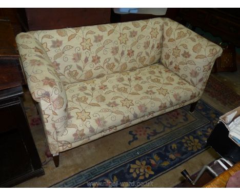 An Edwardian upholstered Sofa standing on tapering square front legs and upholstered pale beige and stylized floral fabric.