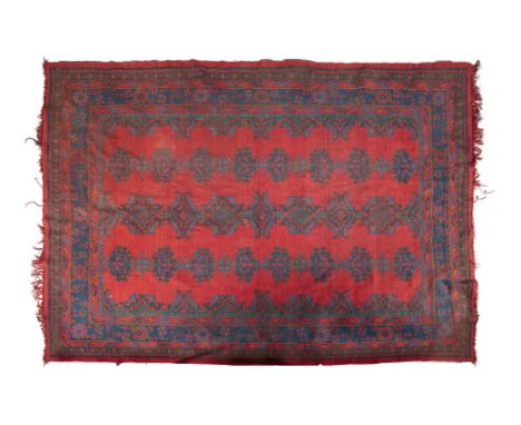 AN ANTIQUE TURKISH WOOL CARPET, the iron red ground decorated with traditional pattern in deep blues and green with multiple 
