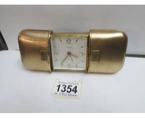 An Estyma engine turned gold plated cushion cased travel clock