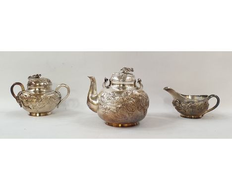 Chinese sterling white metal three-piece tea service, viz:- teapot with swing handle, dragon's head finial and relief dragon 