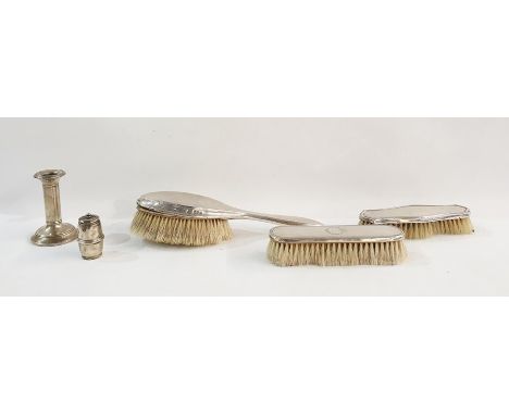 Three assorted silver-backed dressing table brushes, weighted silver candlestick and a weighted&nbsp;silver pepperette in dru