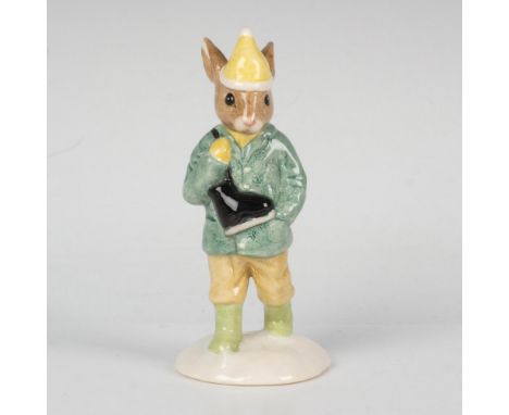 A bunny wearing a dark green jacket, light brown pants, light green boots, and carrying a pair of ice skates. This item comes