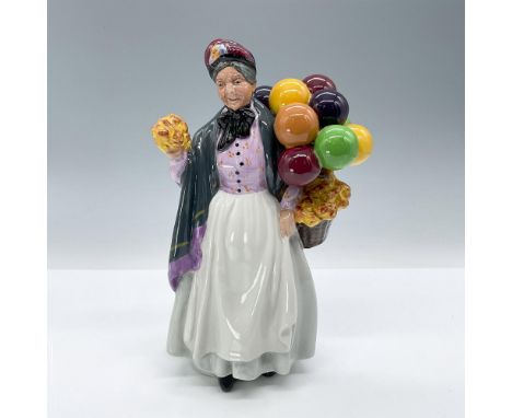 The figure is wearing a pink blouse with a delicate hand-painted pattern, a simple white skirt and apron, a black scarf aroun