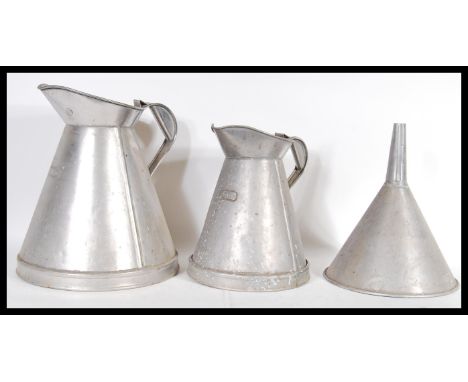 Two vintage industrial dairy milk jugs of graduating size measuring two gallons and one gallon along with a matching funnel.&