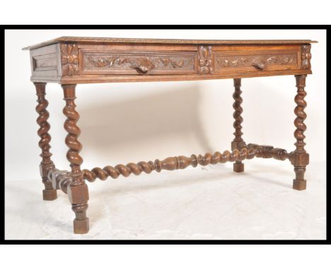 A 19th Century Victorian carved oak library sofa table writing desk raised on barley twist and block supports with twin drawe