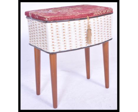 A vintage retro 20th Century sewing box raised on cylindrical tapering legs with white wicker body and red floral upholstery 