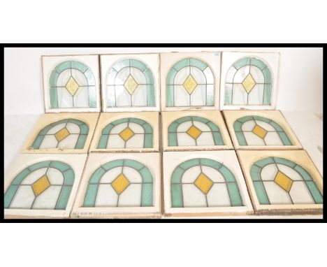 A set of 12 Art Deco leaded and stained glass windows (circa 1928) having domed tops with light blue panes to the edges with 