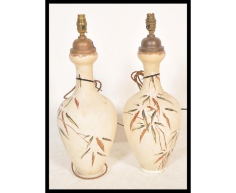 A pair of early 20th Century ceramic table lamp vases having hand painter floral sprays and patterns.