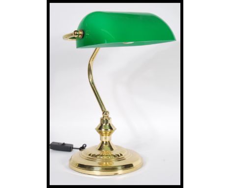 A vintage 20th century bankers desk lamp having an adjustable green glass shade raised on a brass support and good brass base