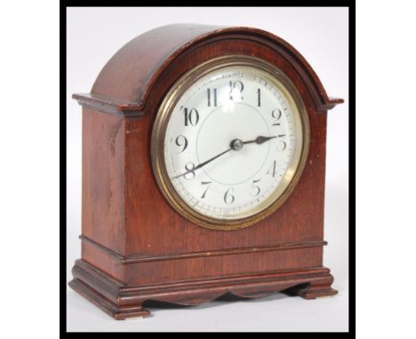 A 20th Century mantel clock having a mahogany case of domed form with a round white enamelled face, having roman numerals to 