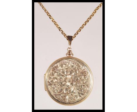 A 9ct gold round shaped hallmarked locket with engine turned decoration being set to a 9ct gold hallmarked necklace chain. Le