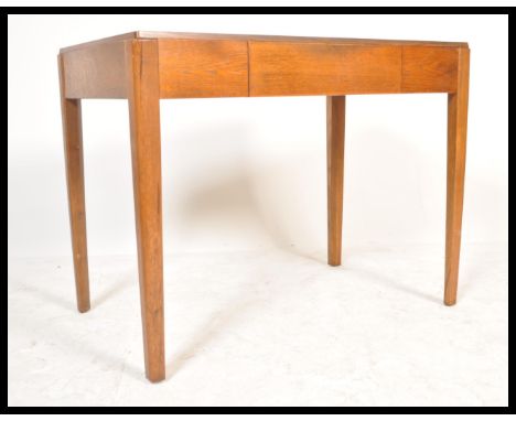 A vintage mid 20th Century golden oak Utility writing table desk being raised on squared tapering supports, single drawer to 