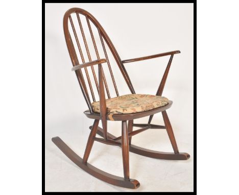 A vintage retro 20th Century Ercol spindle back rocking chair having a hooped back and a fitted seat cushion. Measures 84 cm 