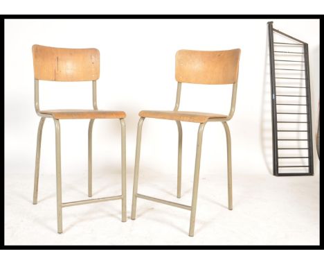 A pair of vintage retro 20th Century tubular stacking chairs having plywood seats and backrests. Measures 97 cm high.